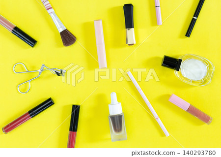 Bright yellow background with assorted makeup tools. Brushes, eyeliner, lipstick, and a small bottle are scattered. Each item is neatly placed for easy viewing Bright yellow background with assorted makeup tools. Brushes, eyeliner, lipstick, and a small bottle are scattered. Each item is neatly placed for easy viewing 140293780