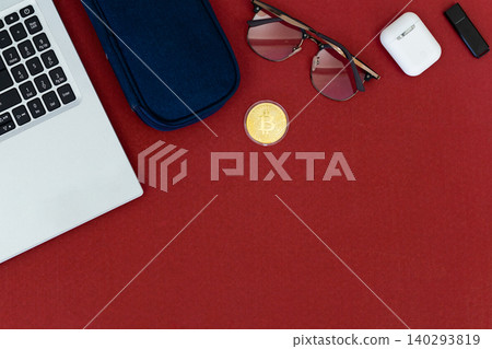 Red surface holds tech and accessories. Laptop, phone, earbuds, and sunglasses rest nearby. Small plant adds green contrast to bold red. Cozy, stylish, modern scene for digital lifestyles Red surface holds tech and accessories. Laptop, phone, earbuds, and sunglasses rest nearby. Small plant adds green contrast to bold red. Cozy, stylish, modern scene for digital lifestyles 140293819