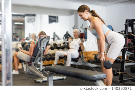 Portrait of a sporty girl doing exercises with dumbbells in gym Portrait of a sporty girl doing exercises with dumbbells in gym 140293871
