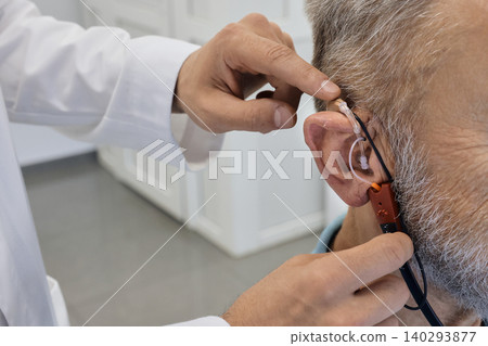 Audiologist customizes a hearing aid to improve an individual's audio experience with advanced techniques, close-up. Real ear measurements 140293877