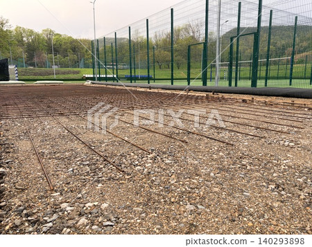 a construction site adjacent to a fenced sports field. An ongoing infrastructure or facility expansion project 140293898