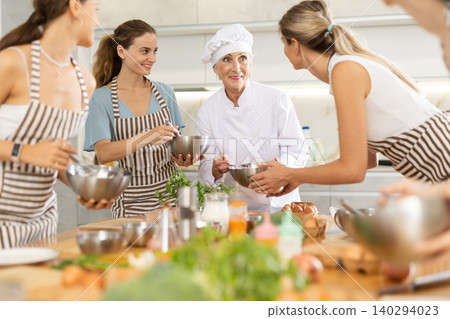 Mature female cook holding bowl and whisk Mature female cook holding bowl and whisk 140294023