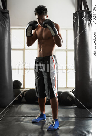 Man, gloves and guard pose in gym with punching bag for fitness, sports and training for competition. Male person, Muay Thai and fist with arms up for fighting, performance and workout at club studio Man, gloves and guard pose in gym with punching bag for fitness, sports and training for competition. Male person, Muay Thai and fist with arms up for fighting, performance and workout at club studio 140294069