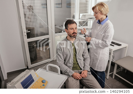 Adult man while tympanometry or impedance audiometry and test of middle-ear function with audiologist using tympanometer probe at hearing center Adult man while tympanometry or impedance audiometry and test of middle-ear function with audiologist using tympanometer probe at hearing center 140294105