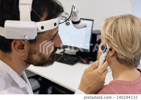 Close-up of audiologist checking senior woman ear with an otoscope during a hearing test in an audiology clinic Close-up of audiologist checking senior woman ear with an otoscope during a hearing test in an audiology clinic 140294132