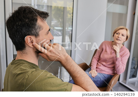 Hearing aids. Two individuals share a meaningful conversation, showcasing the support of a hearing aid in enhancing communication Hearing aids. Two individuals share a meaningful conversation, showcasing the support of a hearing aid in enhancing communication 140294139