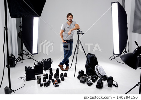Photographer, happy or lighting with equipment in studio for career, behind the scenes or camera. Photography, guy and confidence with electronics, portrait or shooting gear for photoshoot or passion Photographer, happy or lighting with equipment in studio for career, behind the scenes or camera. Photography, guy and confidence with electronics, portrait or shooting gear for photoshoot or passion 140294150