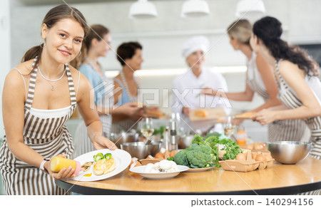 Girl visitors to culinary school decorates finished dish, fried chicken fillet with golden crust 140294156