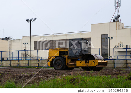 Yellow road roller rests on dirt terrain Yellow road roller rests on dirt terrain 140294256