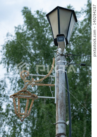 Metal street lamp pole supports a vintage lantern Metal street lamp pole supports a vintage lantern 140294287