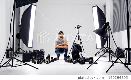 Photographer, portrait or lighting with equipment in studio for career, behind the scenes or camera. Photography, guy and confidence with electronics, flash or shooting gear for photoshoot or passion Photographer, portrait or lighting with equipment in studio for career, behind the scenes or camera. Photography, guy and confidence with electronics, flash or shooting gear for photoshoot or passion 140294293