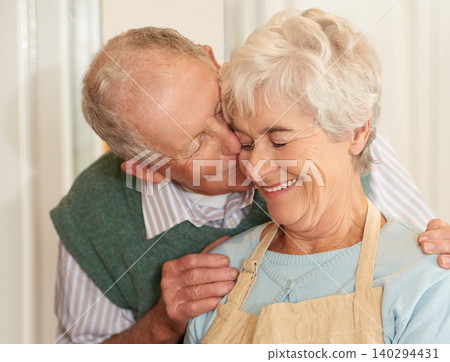 Senior couple, romance and kiss at home, smile and bonding together in retirement. Elderly people, love and happy in marriage or relationship, weekend and support in commitment or care in kitchen Senior couple, romance and kiss at home, smile and bonding together in retirement. Elderly people, love and happy in marriage or relationship, weekend and support in commitment or care in kitchen 140294431