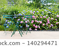 A garden table and chairs placed on a terrace where hydrangeas are in bloom. 140294471