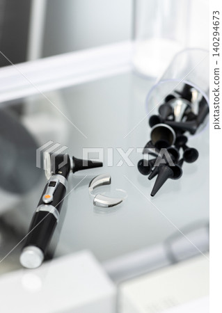 Close-up of hearing clinic tools, featuring an otoscope and ear tips for examination and fitting. Hearing exam concept 140294673