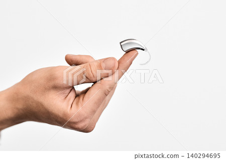 Compact, modern hearing aid for treatment of hearing loss lying on finger of audiologist. Concept of invisibility of modern hearing aids Compact, modern hearing aid for treatment of hearing loss lying on finger of audiologist. Concept of invisibility of modern hearing aids 140294695