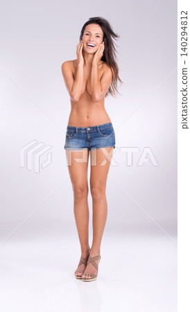 Portrait, smile and shorts with naked woman in studio on gray background for feminine confidence. Fashion, sexy and shirtless with body of happy young model in denim for style or natural sensuality Portrait, smile and shorts with naked woman in studio on gray background for feminine confidence. Fashion, sexy and shirtless with body of happy young model in denim for style or natural sensuality 140294812