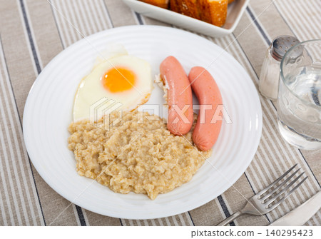 Continental breakfast for one person - portion of oatmeal, fried egg and sausage 140295423