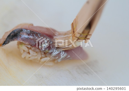 在竹莢魚握壽司上刷一層煮熟的醬油。 在竹莢魚握壽司上刷一層煮熟的醬油。 140295601