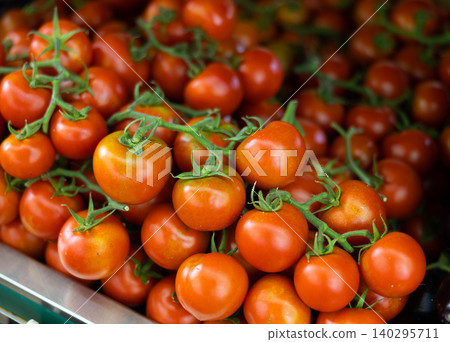 Red tomatoes on branches displayed in crates on market stall Red tomatoes on branches displayed in crates on market stall 140295711
