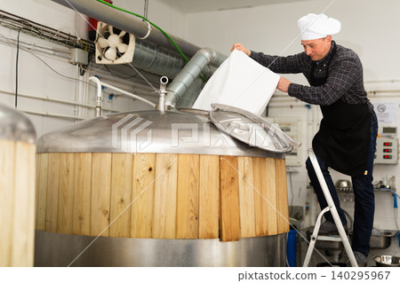 Brewer pouring malted grain from bag into fermenter to produce beer Brewer pouring malted grain from bag into fermenter to produce beer 140295967
