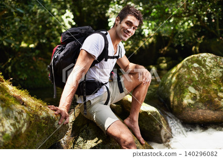Man, portrait and river for hiking in rainforest with smile for adventure, holiday and backpack in summer. Person, happy and bag for trekking, outdoor and journey on rocks for vacation in Colombia 140296082