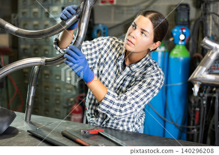 Portrait of a female welder standing with a welding machine and a safety helmet in metal machining workshop Portrait of a female welder standing with a welding machine and a safety helmet in metal machining workshop 140296208
