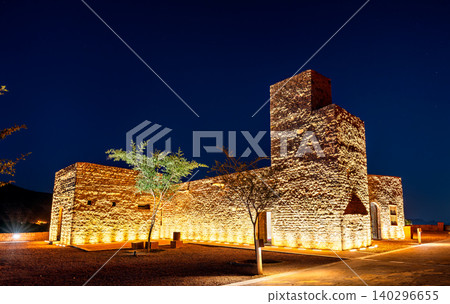 The historic AlUla Fort illuminated by warm lights under a starry night sky in the Al Madinah Province of Saudi Arabia. 140296655