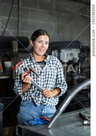 Portrait of young female worker at metallurgical plant with caliper in her hands 140296808