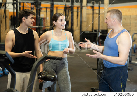 Sporty young girl chatting with male friends in gym 140296890