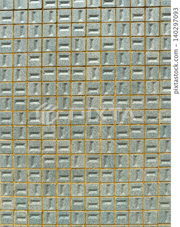 A close up of a geometric wall pattern featuring small light blue textured ceramic tiles arranged in a grid with visible mortar lines throughout A close up of a geometric wall pattern featuring small light blue textured ceramic tiles arranged in a grid with visible mortar lines throughout 140297093