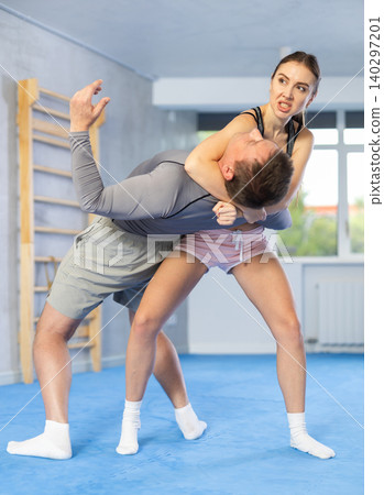 Young woman learning to do power grab on an opponent neck during self-defense training at gym 140297201