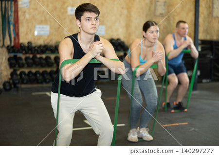 Focused young man training with resistance band for health wellness, strong biceps or abs muscles in gym health center Focused young man training with resistance band for health wellness, strong biceps or abs muscles in gym health center 140297277