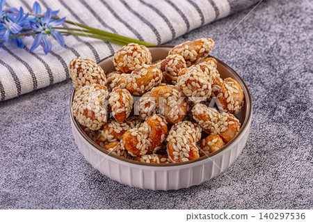 Sweet sesame peanuts snack in ceramic bowl, blue flowers, striped fabric Sweet sesame peanuts snack in ceramic bowl, blue flowers, striped fabric 140297536