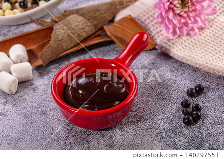 Dark chocolate sauce in red pot, marshmallows, cinnamon, pink flower, cozy still life Dark chocolate sauce in red pot, marshmallows, cinnamon, pink flower, cozy still life 140297551