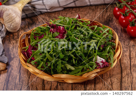 Fresh arugula and radicchio in wicker basket with cherry tomatoes garlic on rustic wood Fresh arugula and radicchio in wicker basket with cherry tomatoes garlic on rustic wood 140297562