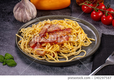 Spaghetti carbonara with crispy bacon and fresh ingredients on dark background Spaghetti carbonara with crispy bacon and fresh ingredients on dark background 140297587