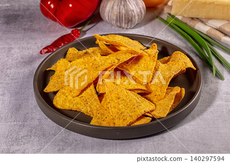 Crispy corn nachos in bowl with fresh ingredients. Mexican appetizer with pepper, garlic, and cheese on gray table 140297594