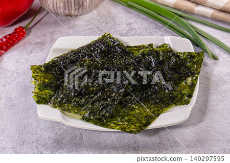 Roasted seaweed snack on white plate with fresh chili garlic and scallions 140297595