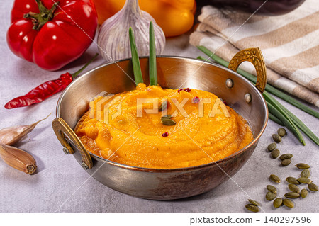 Creamy vegetable puree with pumpkin seeds in metal bowl surrounded by fresh ingredients Creamy vegetable puree with pumpkin seeds in metal bowl surrounded by fresh ingredients 140297596