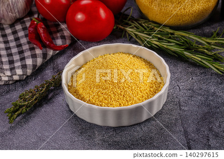 Raw couscous in white bowl with fresh tomatoes, garlic, and herbs on dark background Raw couscous in white bowl with fresh tomatoes, garlic, and herbs on dark background 140297615