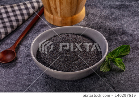 Poppy seeds in grey ceramic bowl with wooden spoon and fresh mint on dark textured background Poppy seeds in grey ceramic bowl with wooden spoon and fresh mint on dark textured background 140297619