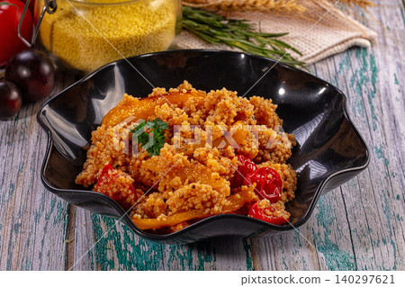 Couscous salad with roasted peppers and tomatoes in black bowl on rustic table Couscous salad with roasted peppers and tomatoes in black bowl on rustic table 140297621