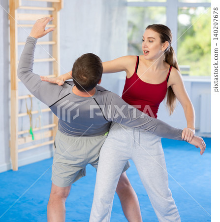 Young girl practicing self-defense techniques in pair with middle-aged man Young girl practicing self-defense techniques in pair with middle-aged man 140297678