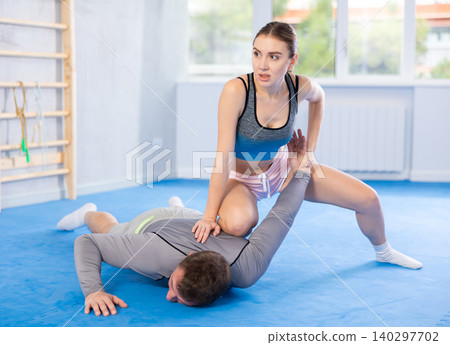 Young woman learns to do painful grip on arm of an attacking man during self defense training Young woman learns to do painful grip on arm of an attacking man during self defense training 140297702