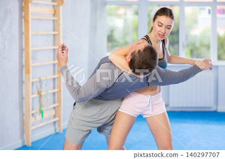 Young woman learning to do power grab on an opponent neck during self-defense training at gym 140297707