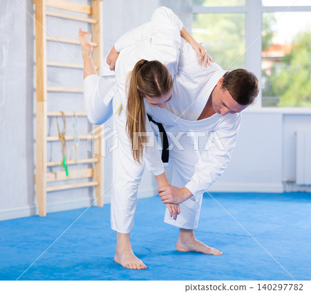 Adult man and young woman training judo fight Adult man and young woman training judo fight 140297782