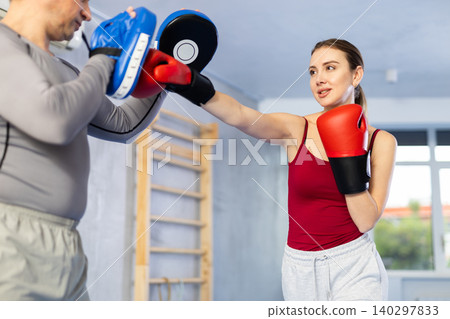 Adult man and young woman practicing boxing Adult man and young woman practicing boxing 140297833