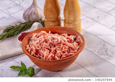 Fresh raw minced meat in terracotta bowl with garlic, pepper, and herbs for cooking 140297944