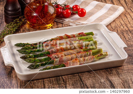 Grilled bacon wrapped asparagus appetizer served on white platter with fresh tomatoes and thyme Grilled bacon wrapped asparagus appetizer served on white platter with fresh tomatoes and thyme 140297960