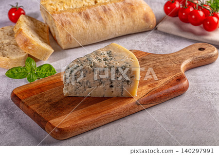 Blue cheese wedge on wooden board with bread and tomatoes Blue cheese wedge on wooden board with bread and tomatoes 140297991